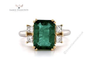 Emerald flanked by two princess-cut diamonds